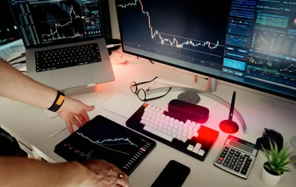 Persona al lavoro con doppio monitor, rappresenta l'adozione di Claude AI nel settore finanziario tramite TCS e DXC