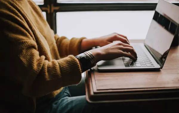 Persona seduta davanti al computer portatile mentre studia