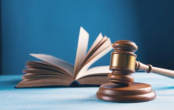 Martello del giudice e libro del diritto, simbolo della causa legale tra Apple e OpenAI