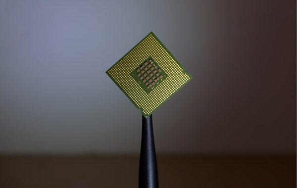 Processore per computer tenuto con pinzette, simbolo della progettazione di chip AI su misura