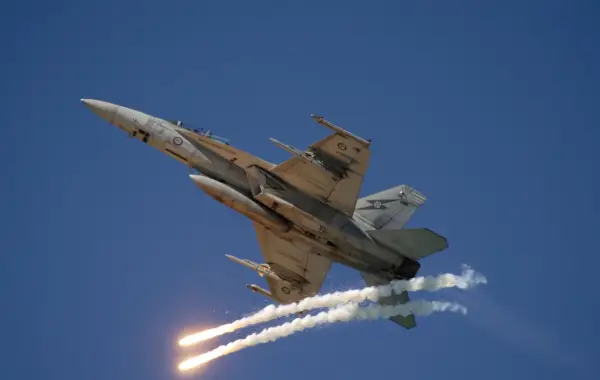 Caccia militare in volo che rilascia flare in un cielo azzurro