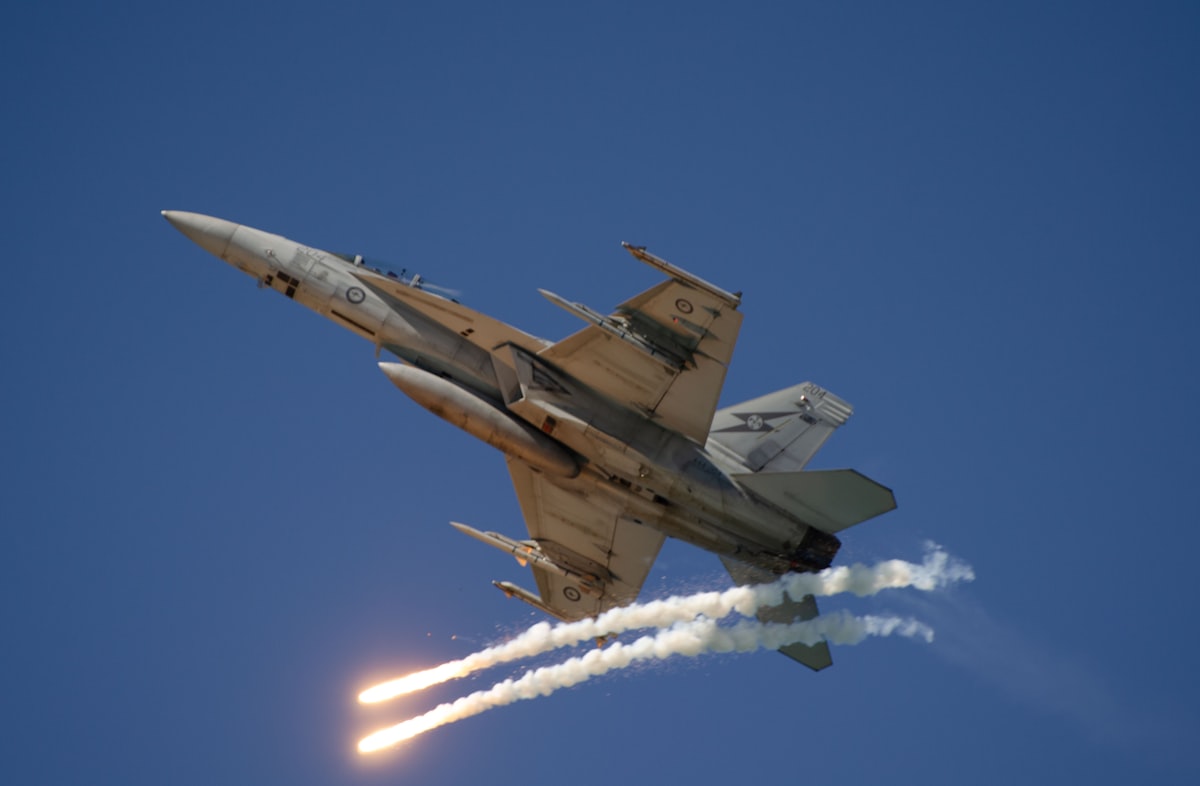 Caccia militare in volo che rilascia flare in un cielo azzurro
