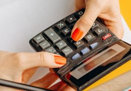 Persona usa una calcolatrice e gestisce le finanze personali su una scrivania con contanti e ricevute