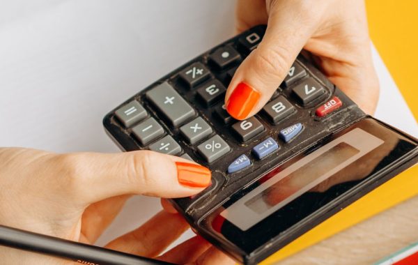 Persona usa una calcolatrice e gestisce le finanze personali su una scrivania con contanti e ricevute