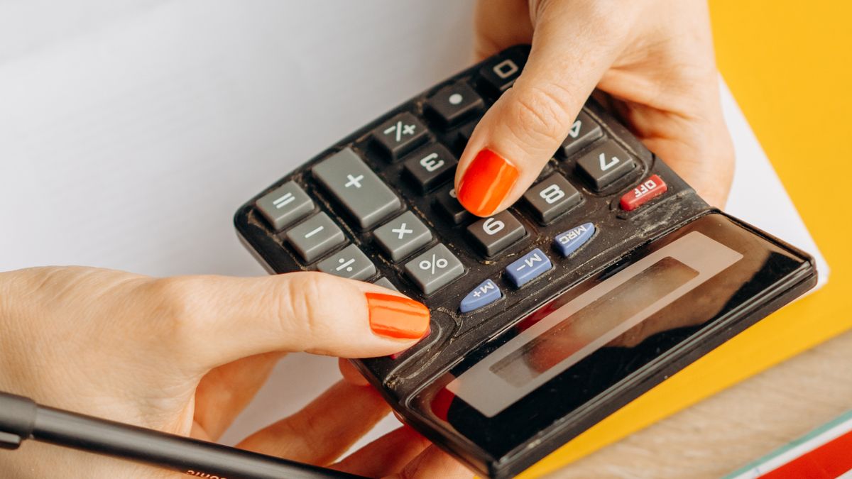Persona usa una calcolatrice e gestisce le finanze personali su una scrivania con contanti e ricevute