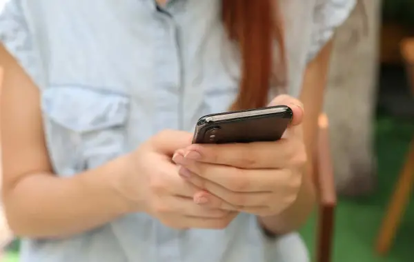 Mano che tiene uno smartphone, immagine simbolica del lancio di ChatGPT for Teens di OpenAI
