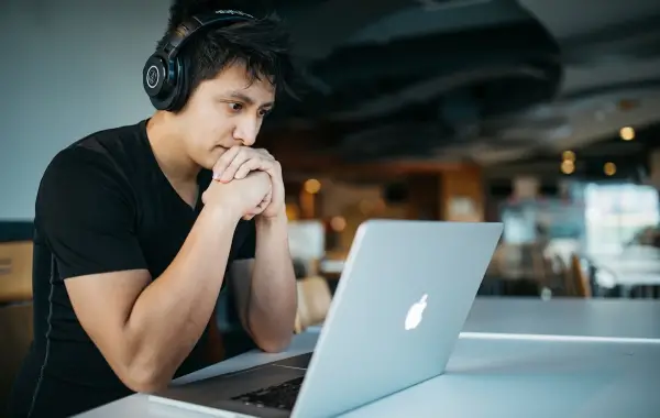 Studente che studia al computer portatile con quaderno e appunti