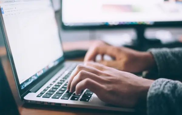 Persona che scrive al laptop usando generatori di testo AI