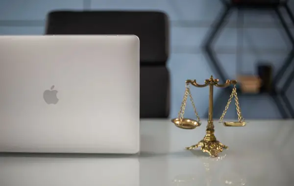 Bilancia della giustizia accanto a un laptop su una scrivania, simbolo del rapporto tra AI e diritto