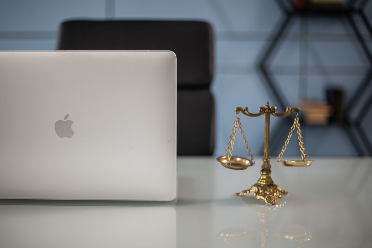 Bilancia della giustizia accanto a un laptop su una scrivania, simbolo del rapporto tra AI e diritto