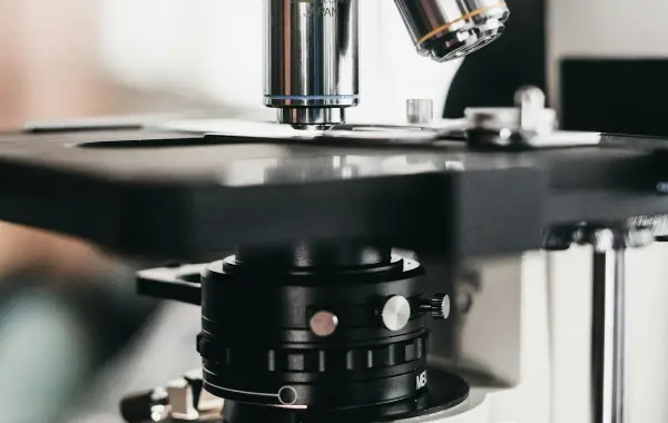 Mano guantata che posiziona un vetrino istologico al microscopio in laboratorio di patologia