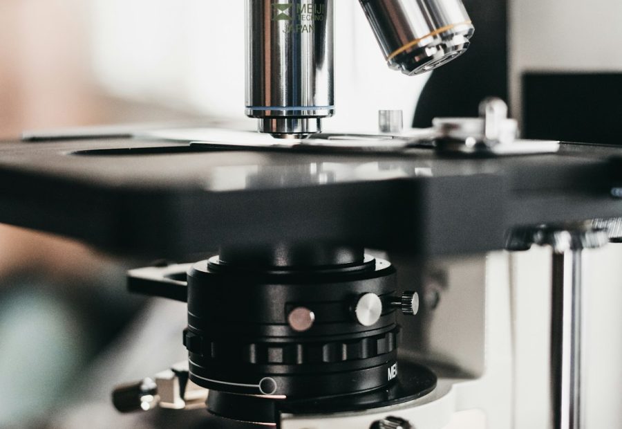 Mano guantata che posiziona un vetrino istologico al microscopio in laboratorio di patologia