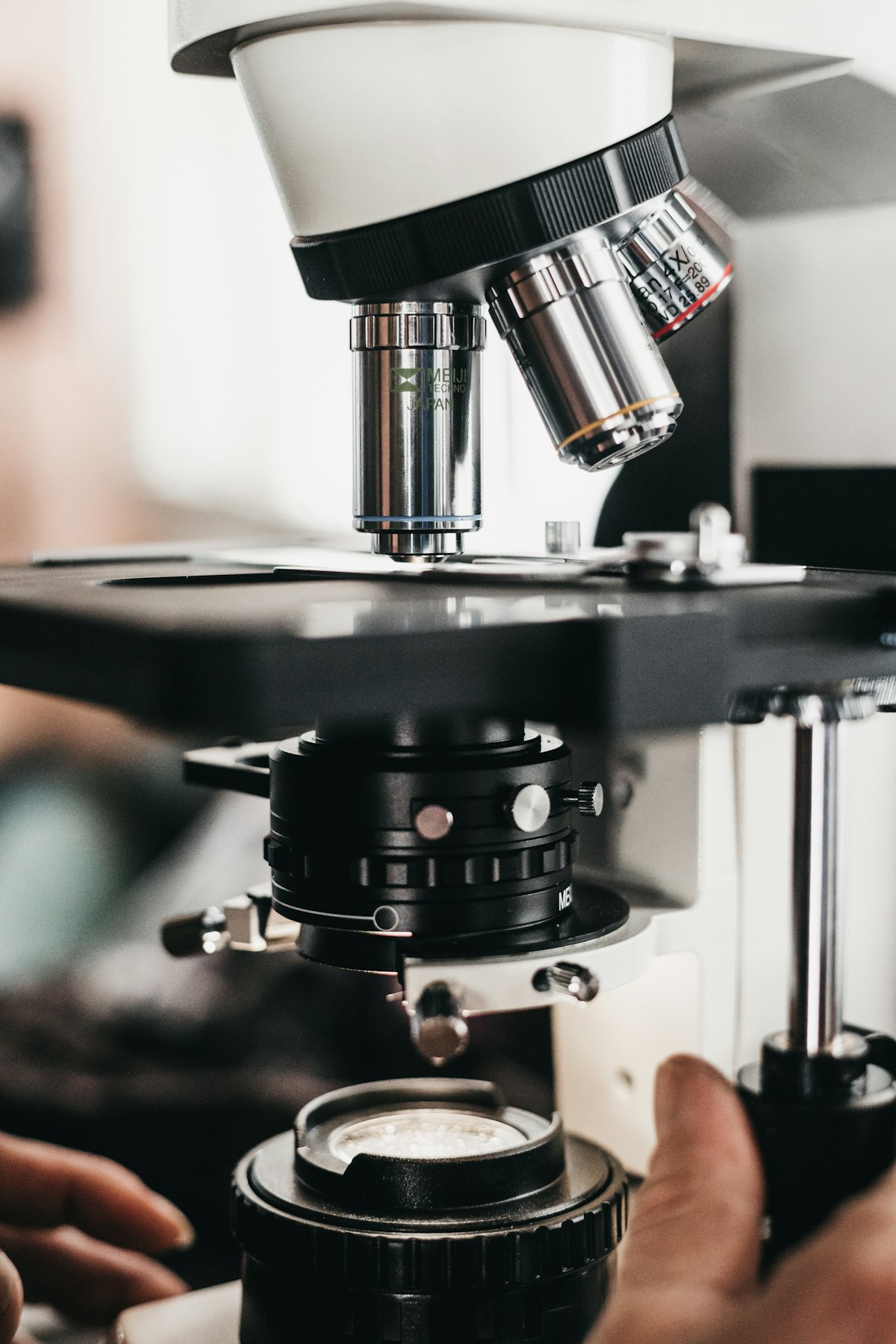Mano guantata che posiziona un vetrino istologico al microscopio in laboratorio di patologia
