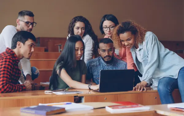 Gruppo di studenti universitari al lavoro attorno a un computer portatile
