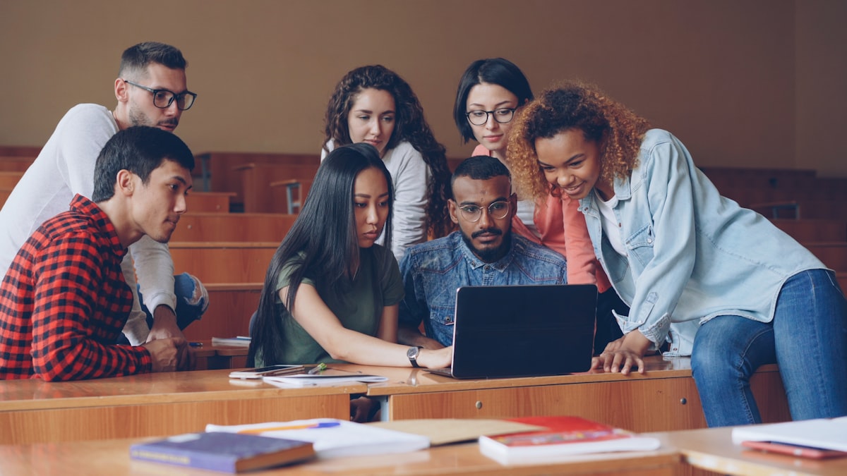 Gruppo di studenti universitari al lavoro attorno a un computer portatile