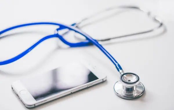 Stetoscopio e smartphone su una superficie bianca, simbolo dell'AI clinica accessibile ai medici