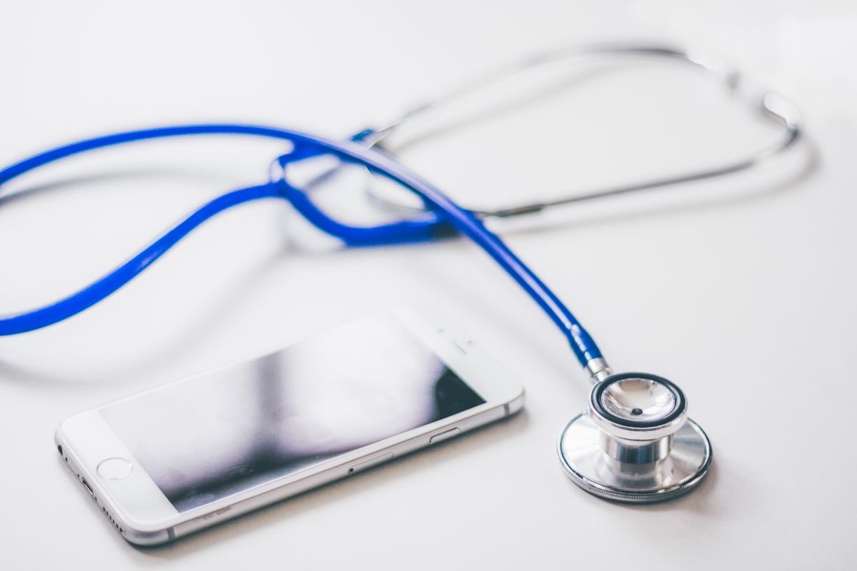 Stetoscopio e smartphone su una superficie bianca, simbolo dell'AI clinica accessibile ai medici