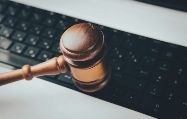 Un martello da giudice di legno appoggiato sulla tastiera di un computer, a simboleggiare le nuove leggi della California sugli audit dei sistemi di intelligenza artificiale