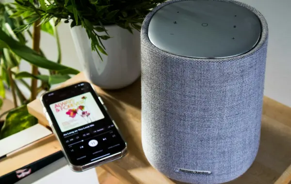 Smartphone collegato a uno smart speaker, simbolo di assistente vocale con app collegate