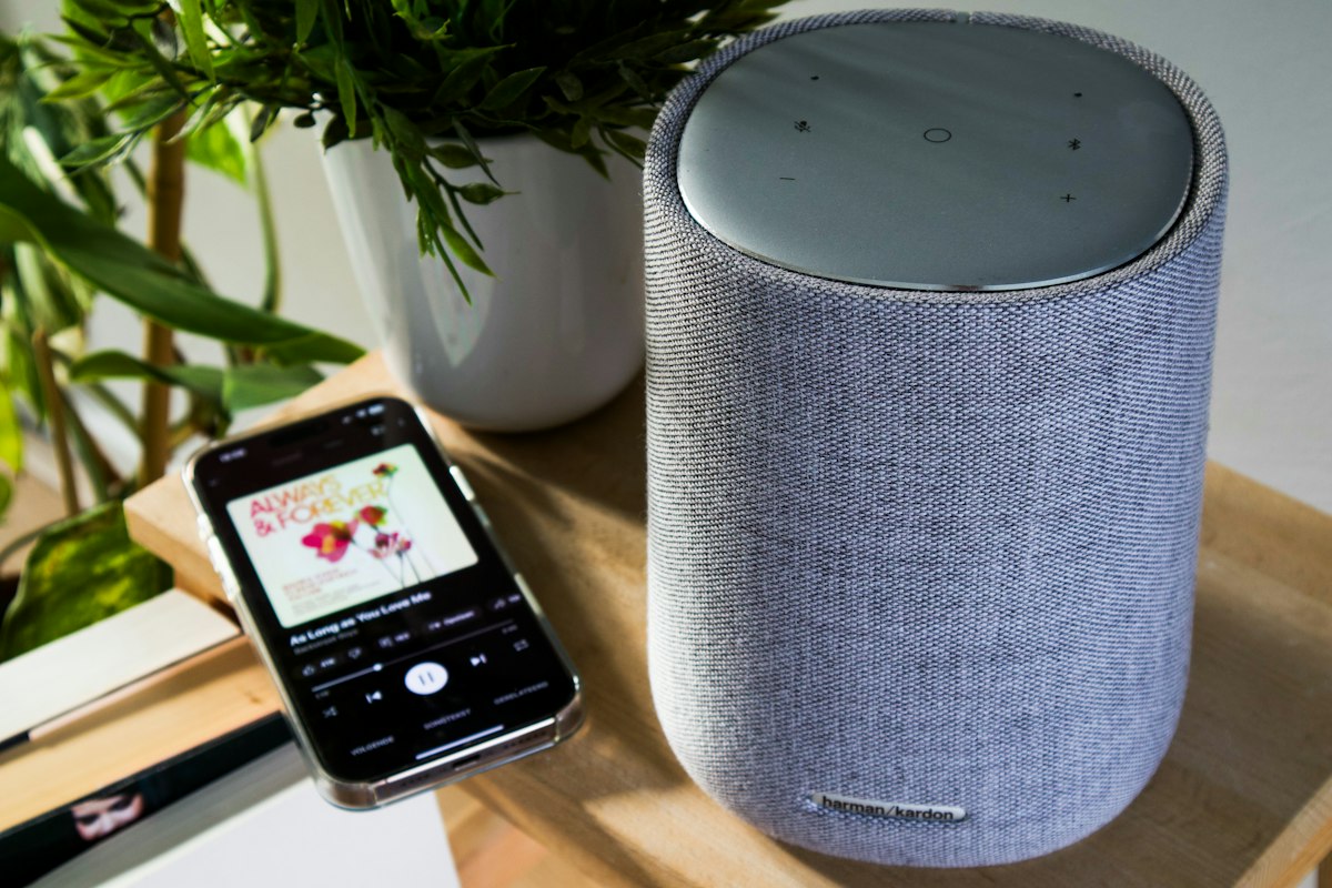 Smartphone collegato a uno smart speaker, simbolo di assistente vocale con app collegate