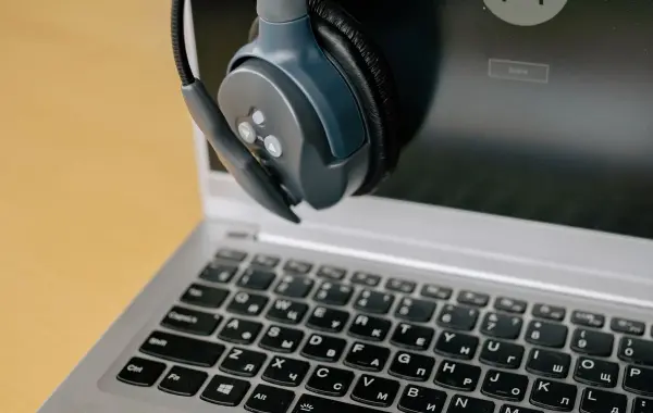 Cuffie con microfono appoggiate su un laptop, simbolo di assistenza clienti con agenti AI