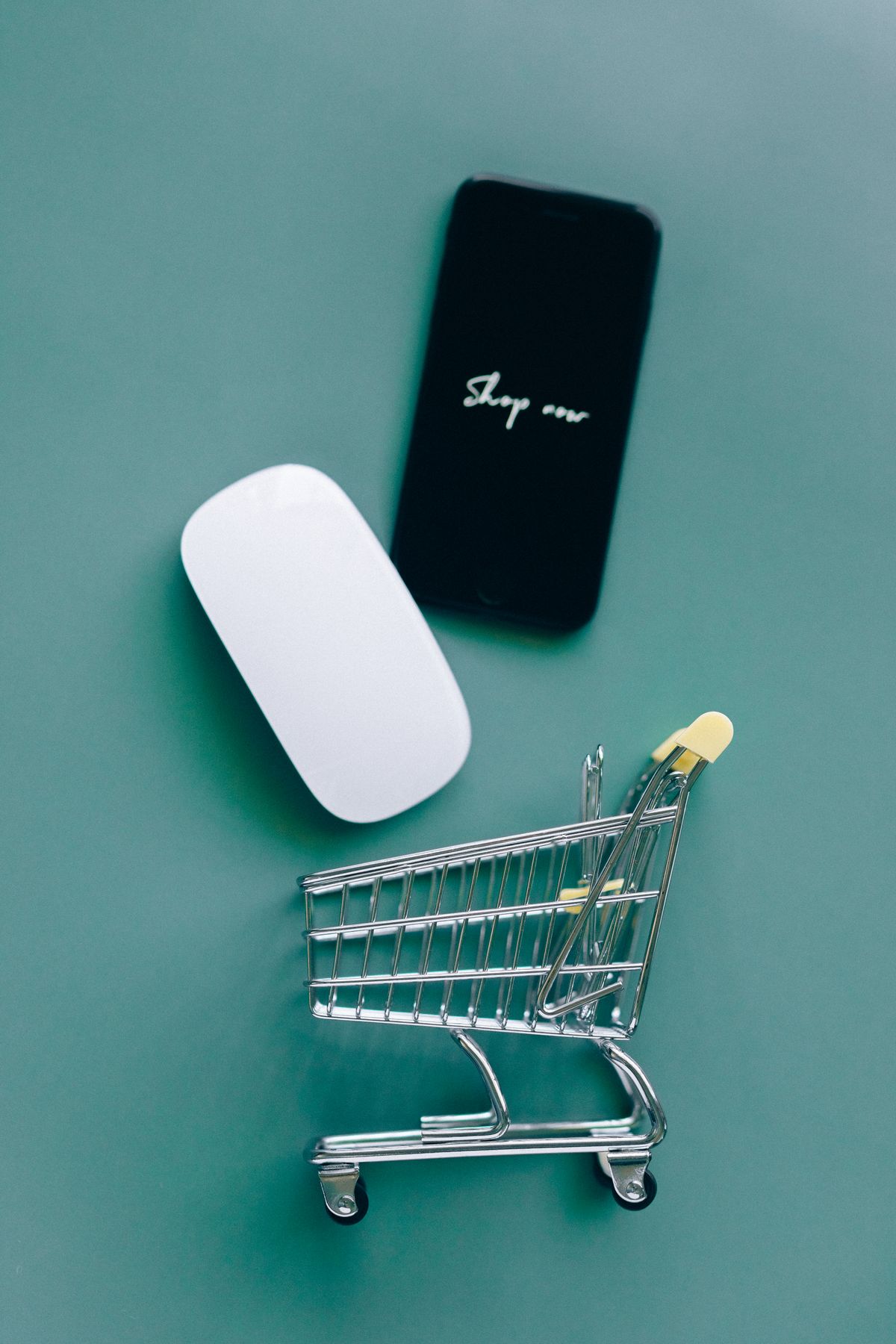 Smartphone appoggiato su un piccolo carrello della spesa, simbolo degli acquisti online tramite assistenti AI