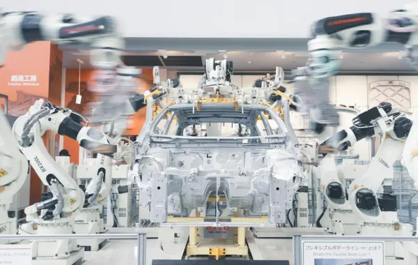 Bracci robotici che assemblano il telaio di un'auto su una linea di produzione industriale