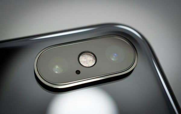 Obiettivo fotocamera di uno smartphone, simbolo della fotografia AI acquisita da OpenAI