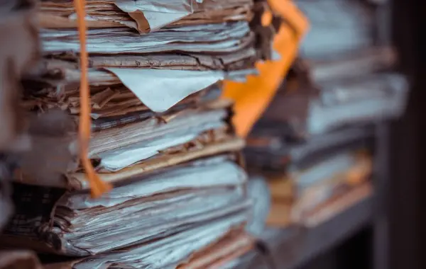 Pile di documenti e fascicoli cartacei accatastati su scaffali, immagine simbolo della digitalizzazione dei documenti con l'AI