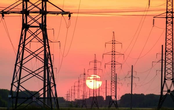 Tralicci dell alta tensione al tramonto, simbolo della rete elettrica sotto pressione per i data center dell intelligenza artificiale