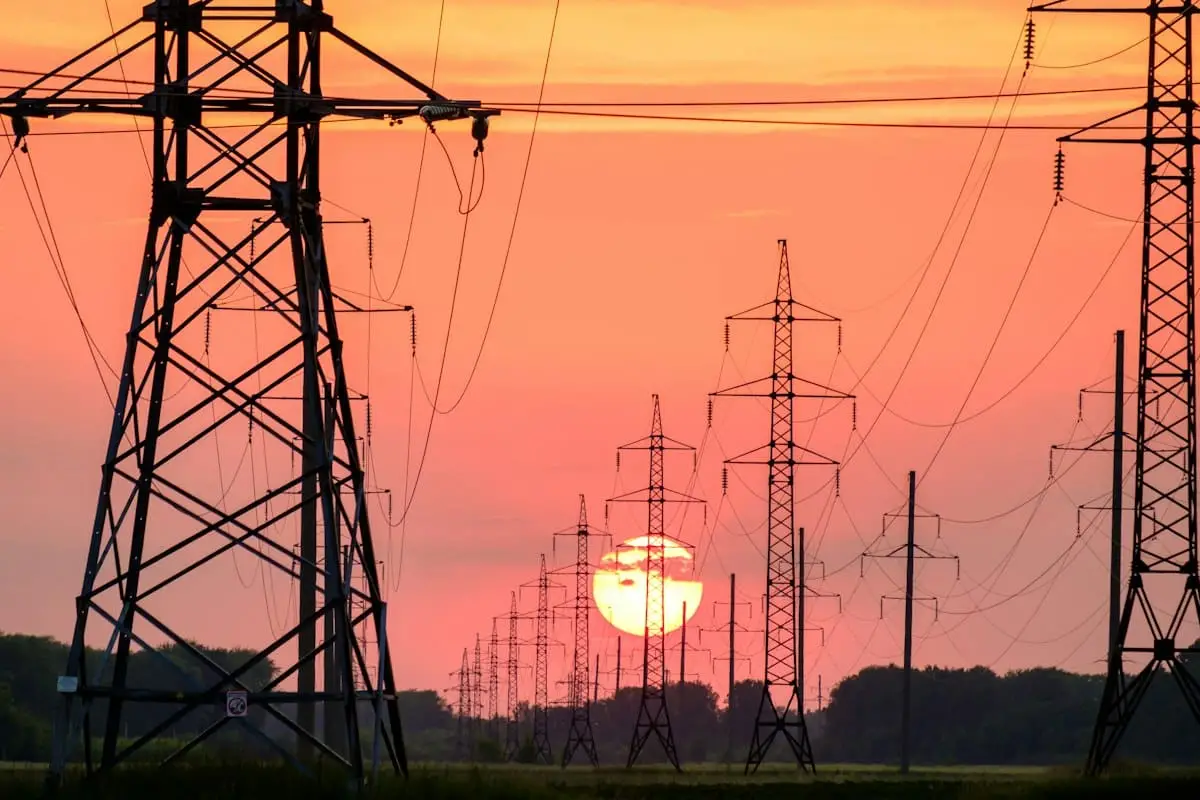 Tralicci dell alta tensione al tramonto, simbolo della rete elettrica sotto pressione per i data center dell intelligenza artificiale