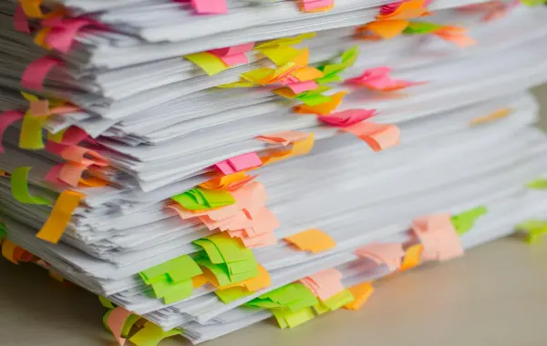 Pila di fogli con linguette adesive colorate, documenti lunghi da riassumere con l'intelligenza artificiale
