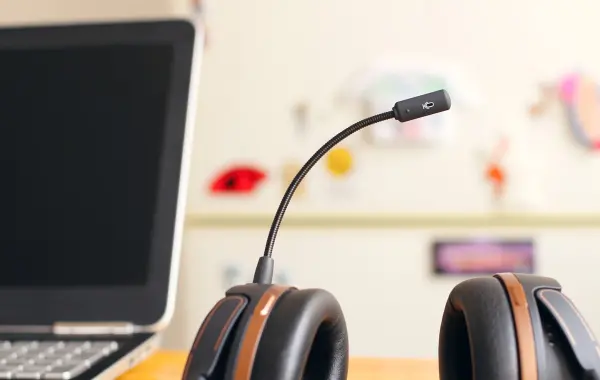 Cuffia con microfono accanto a un computer portatile: AI conversazionale e vocale per il servizio clienti
