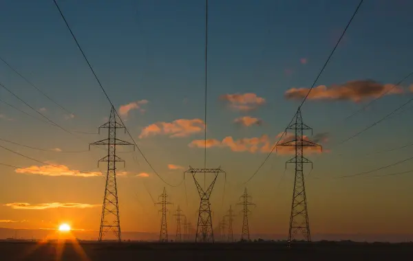 Tralicci e linee elettriche ad alta tensione al tramonto, simbolo delle infrastrutture critiche