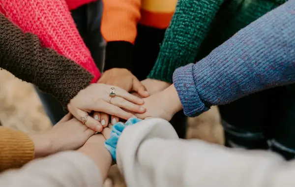 Gruppo di persone con le mani unite al centro in segno di collaborazione