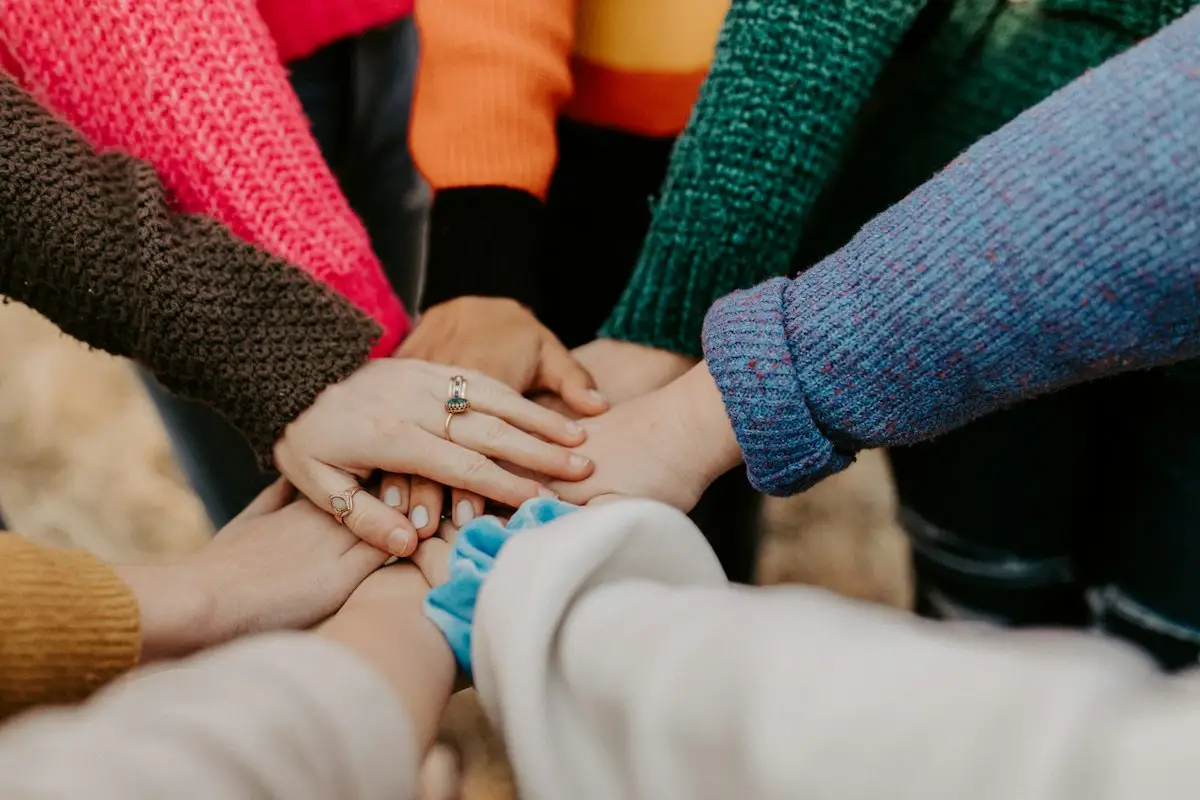 Gruppo di persone con le mani unite al centro in segno di collaborazione