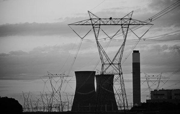 Linee elettriche e torri di raffreddamento di una centrale contro il cielo nuvoloso