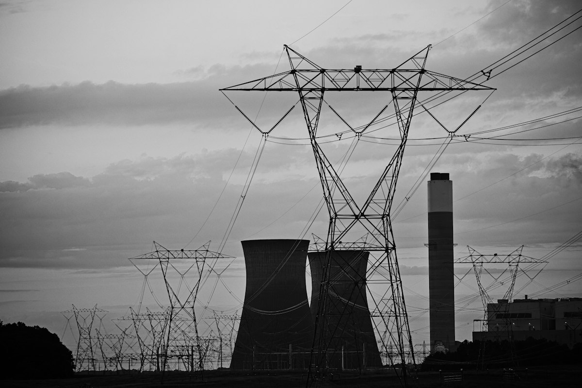Linee elettriche e torri di raffreddamento di una centrale contro il cielo nuvoloso