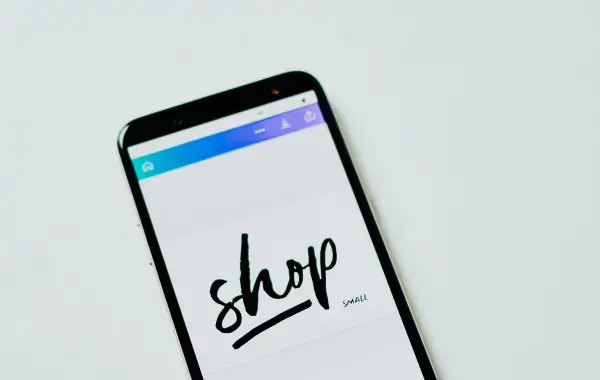 Smartphone con app di shopping online su una superficie bianca