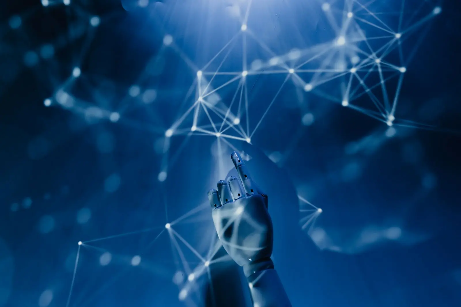 Mano che tocca una rete luminosa di nodi su sfondo blu, simbolo dell'intelligenza artificiale