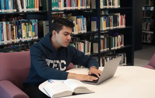 Laptop aperto su una scrivania con appunti e quaderno per studiare
