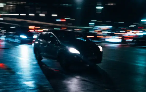 Auto in movimento di notte tra le luci della città